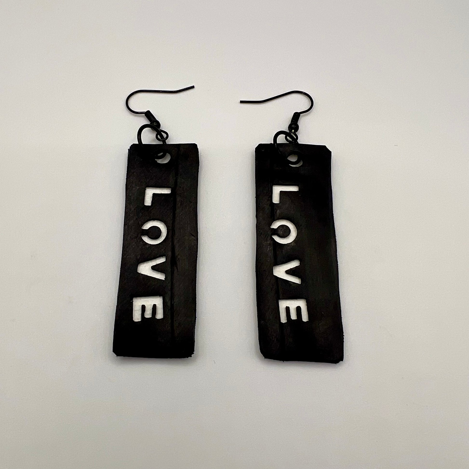 A pair of black and white earrings displaying the word LOVE