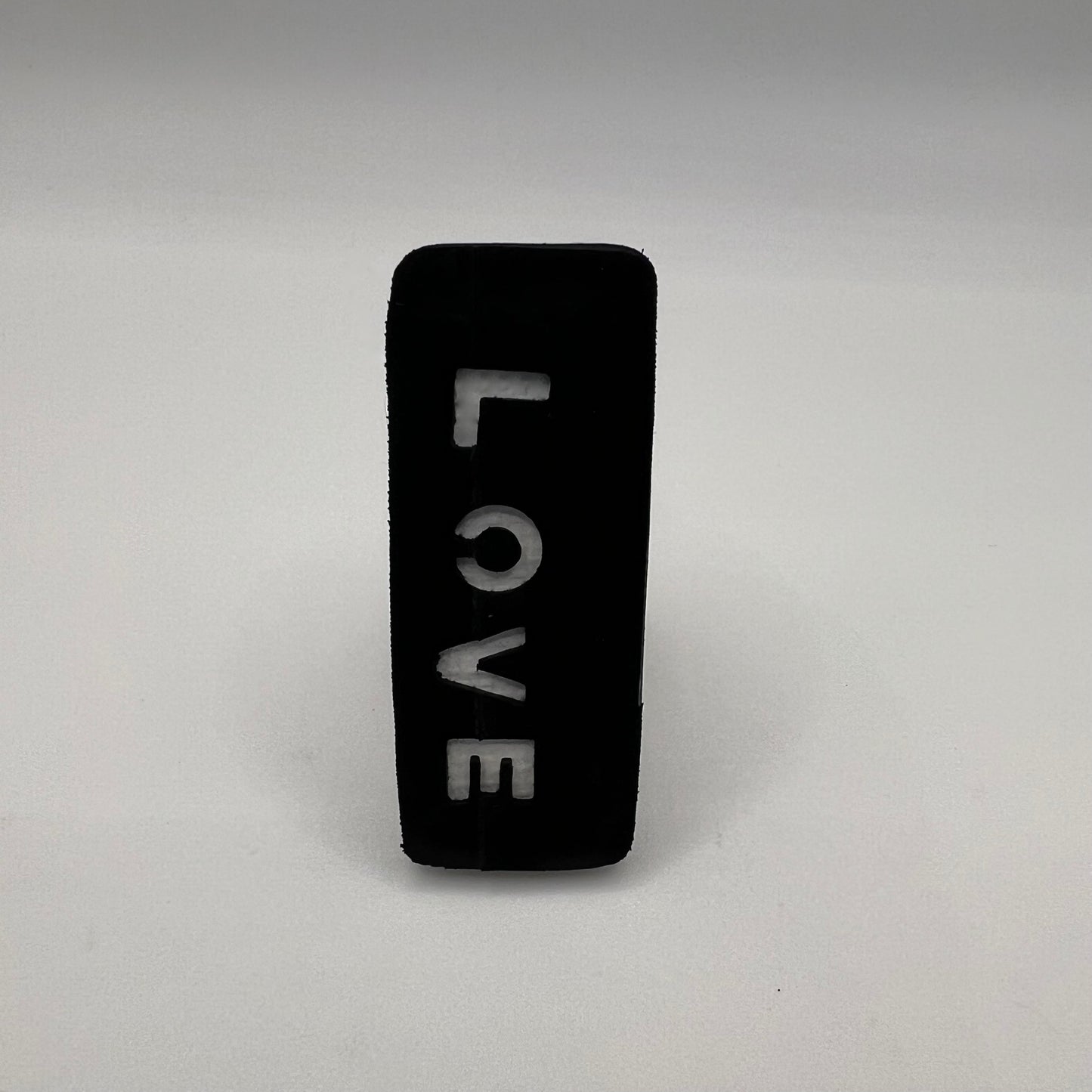 Black rectangular object with 'LOVE' engraved on a gray background