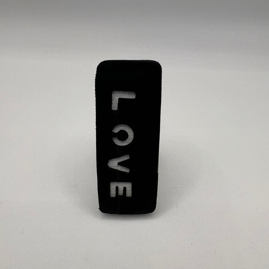 Black rectangular object with 'LOVE' engraved on a gray background