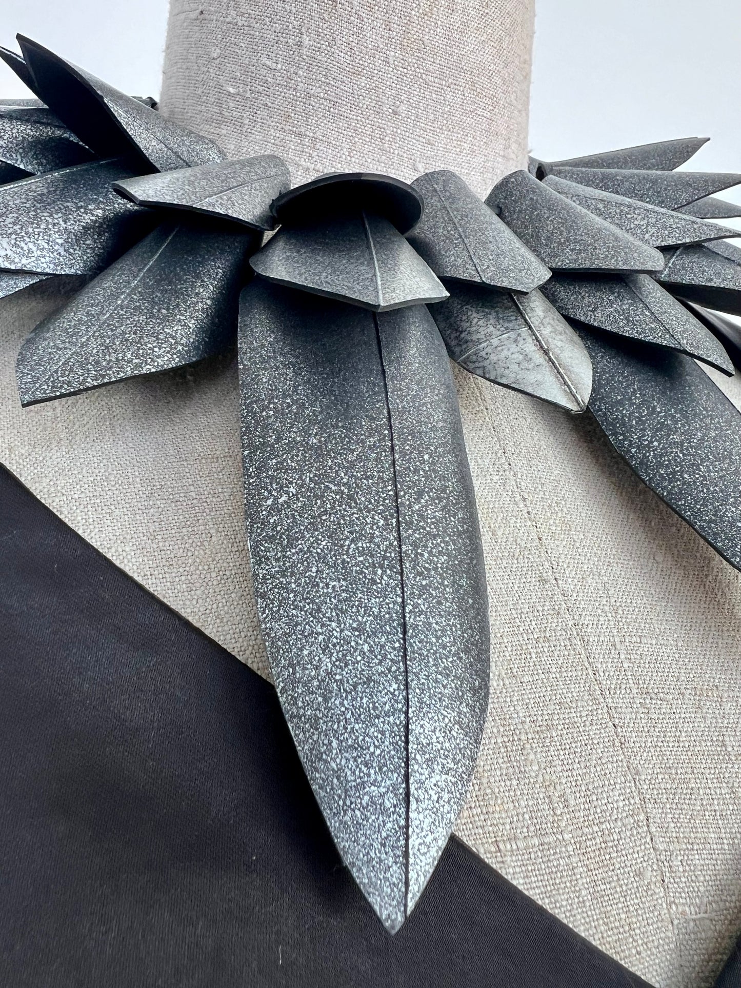 Close up of a pointy silver collar  necklace against a white background