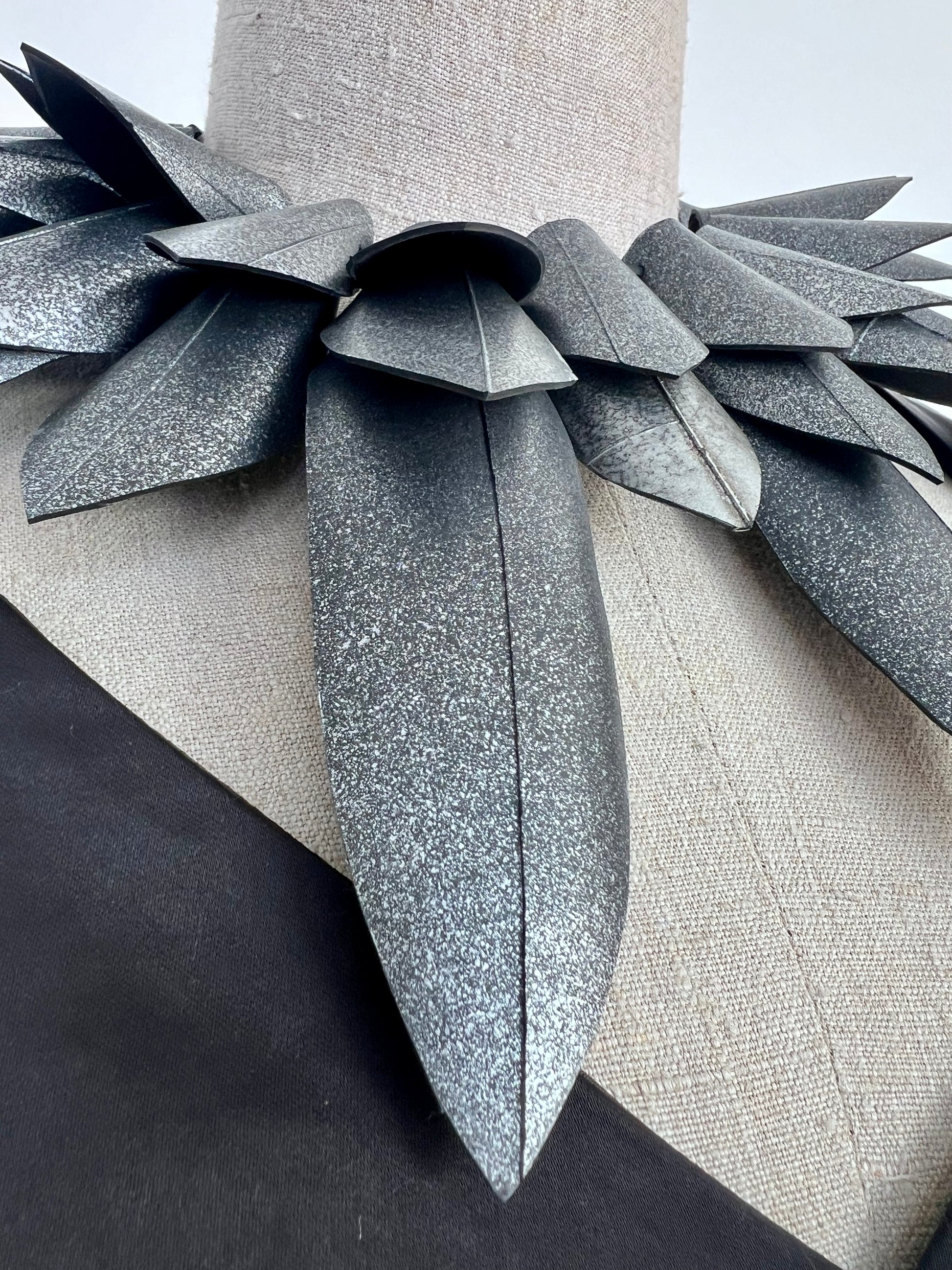 Close up of a pointy silver collar  necklace against a white background