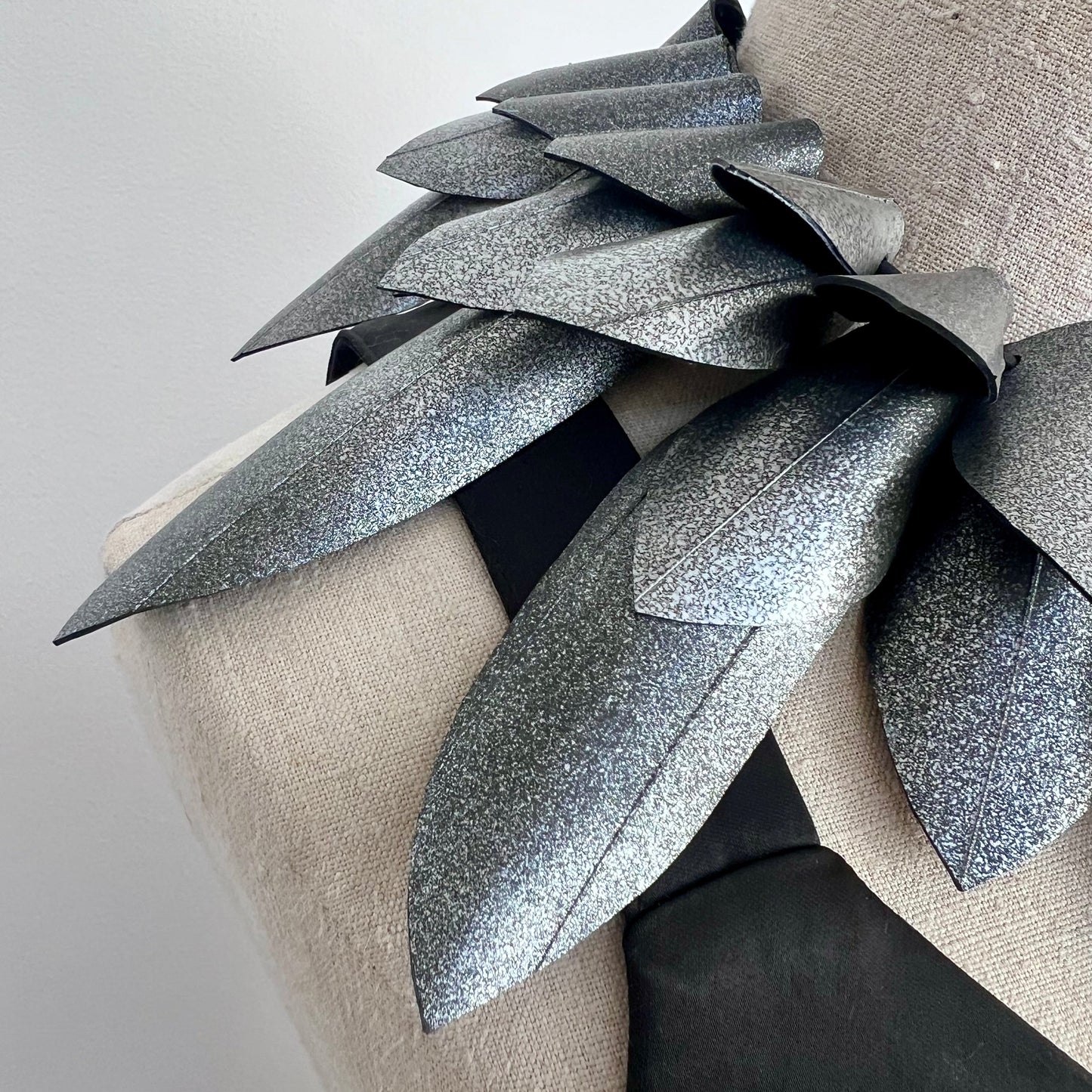 Close up of a pointy silver collar  necklace against a white background