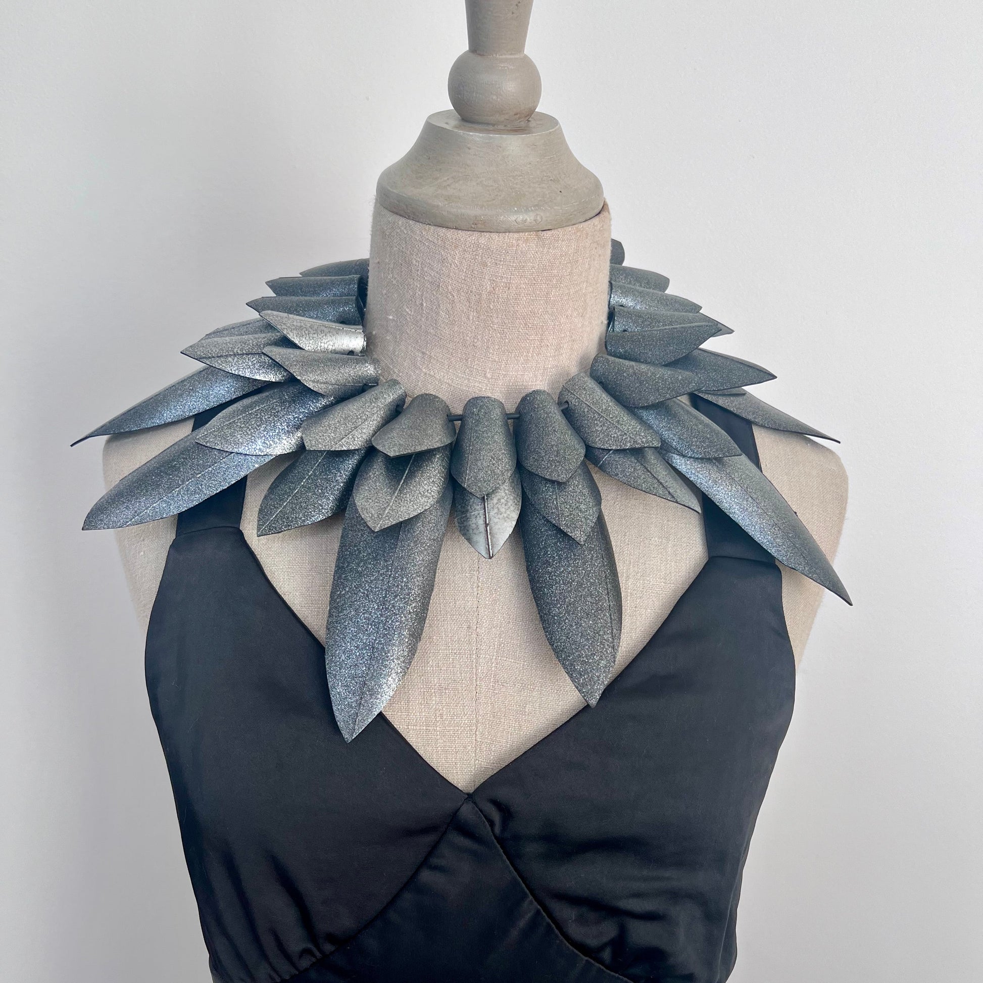 Mannequin wearing a black dress with a large, pointy silver collar against a white background