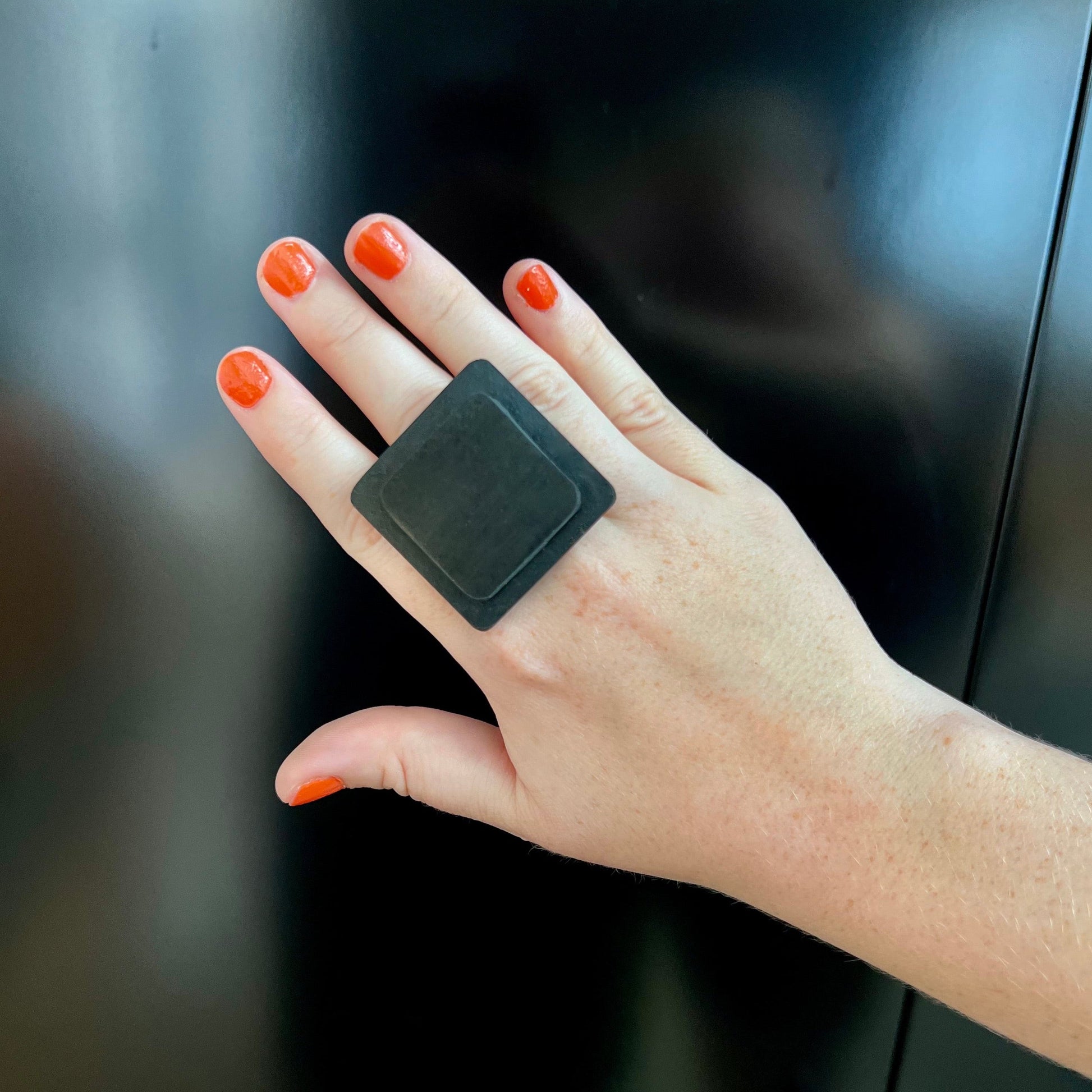 A woman's hand wearing a large repurposed rubber square ring