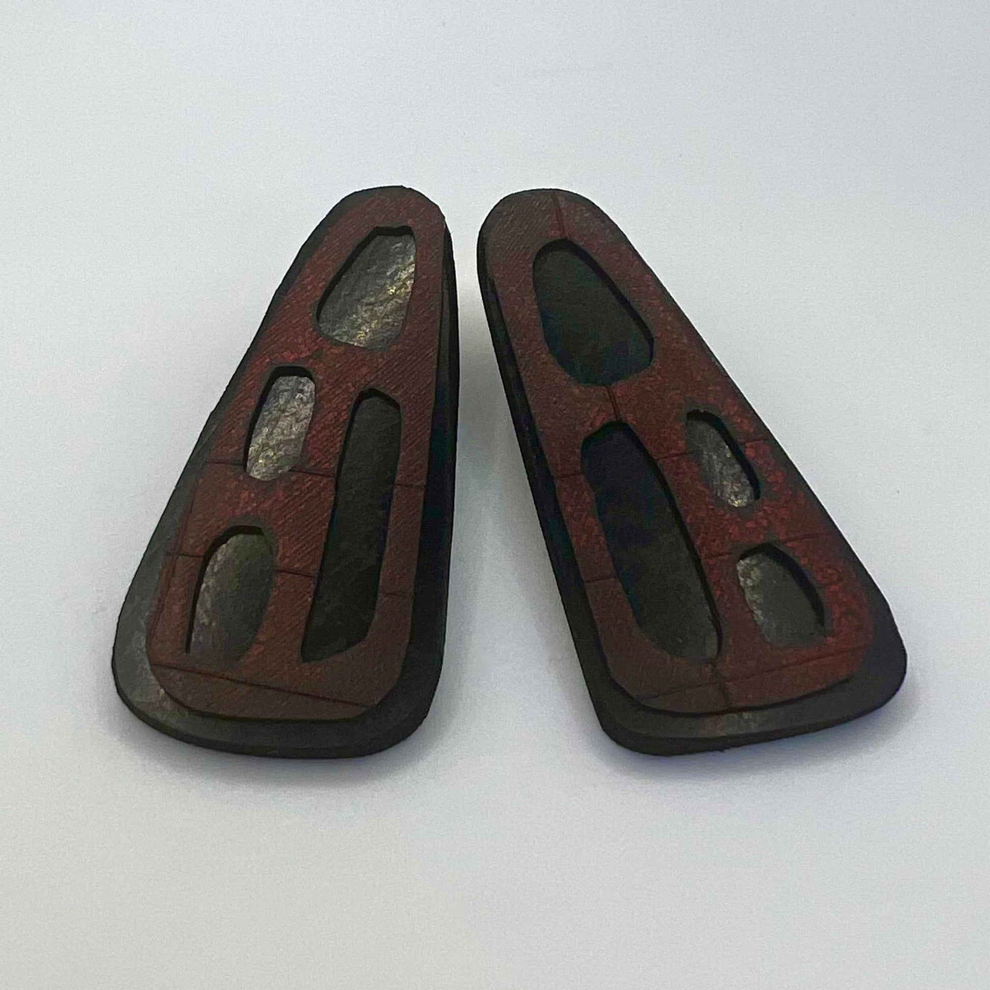 A pair of black rubber stud earrings with an overlay of painted red rubber with organic cut outs