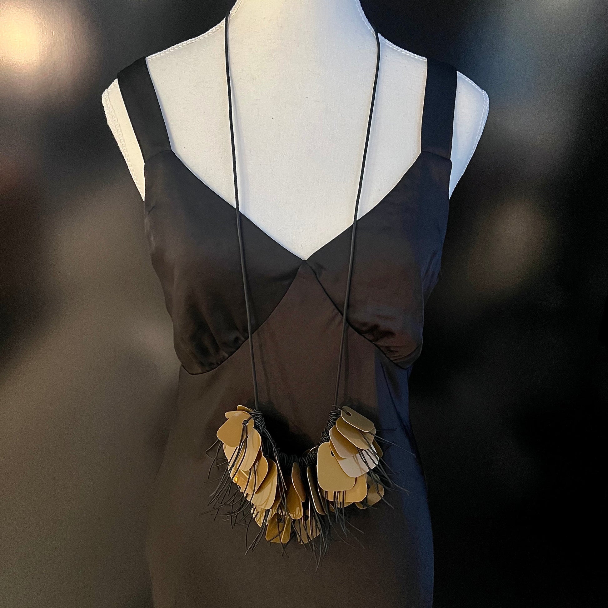 A mannequin wears a necklace made from bronze coloured recycled plastic