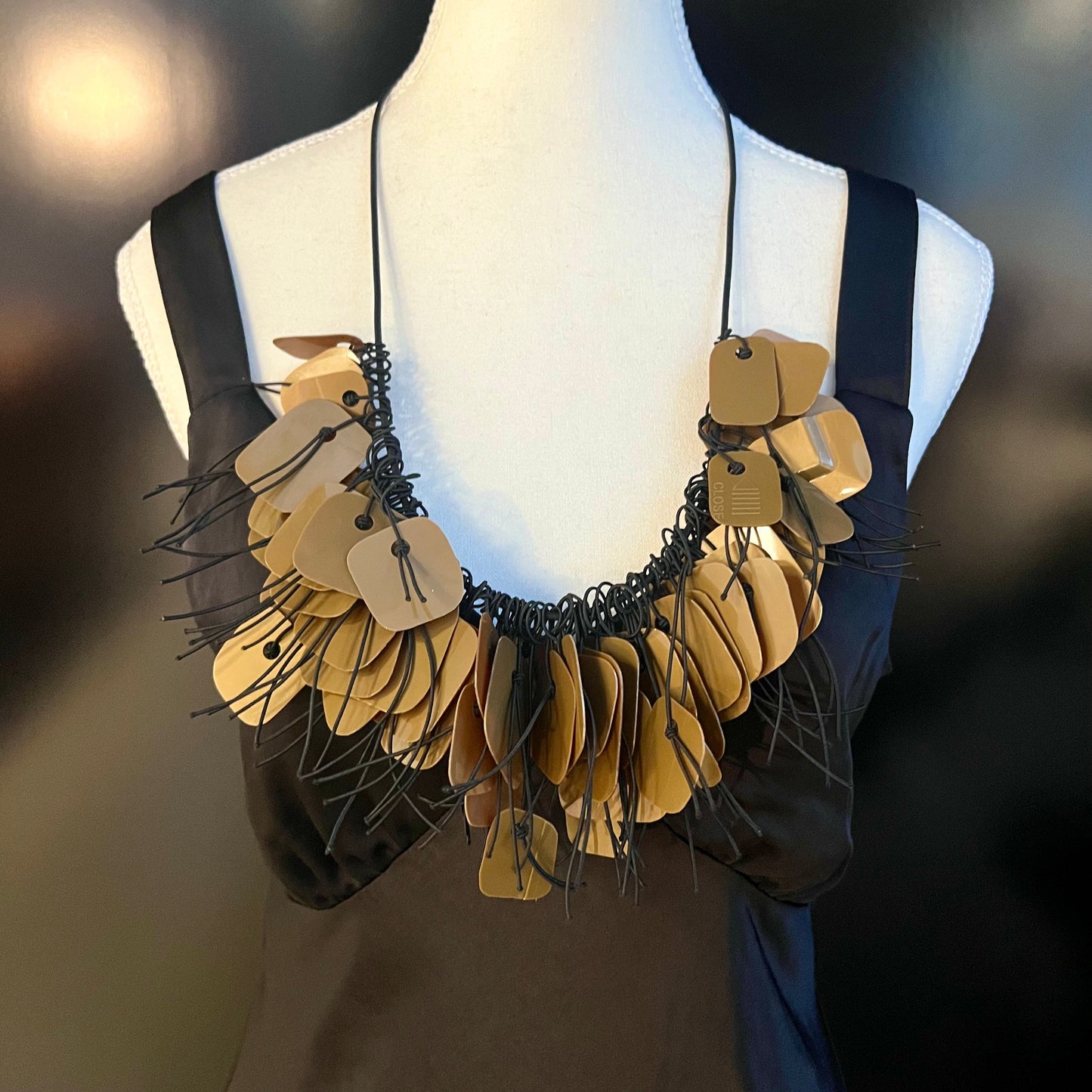 A mannequin wears a necklace made from bronze coloured recycled plastic