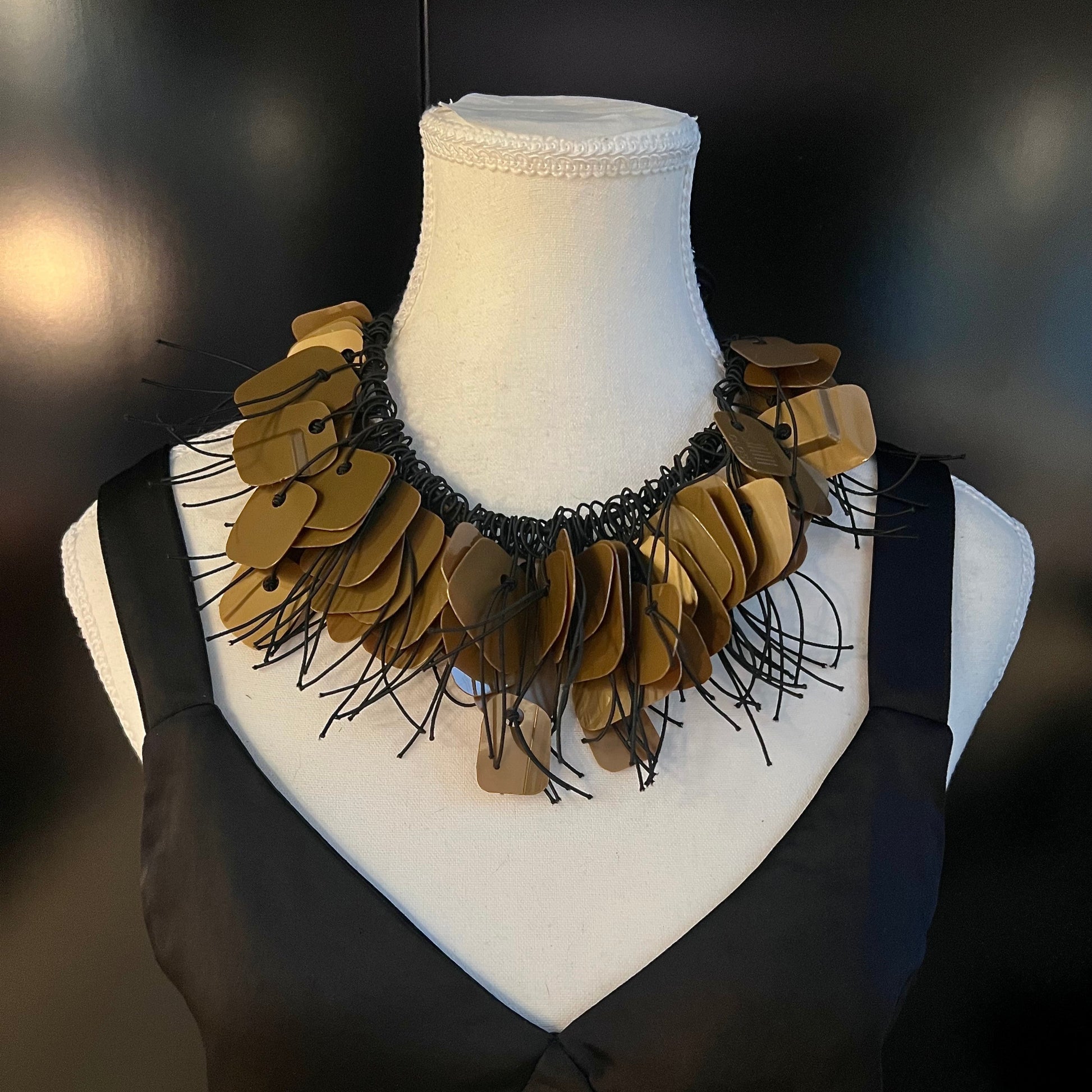 A mannequin wears a necklace made from bronze coloured recycled plastic as a choker