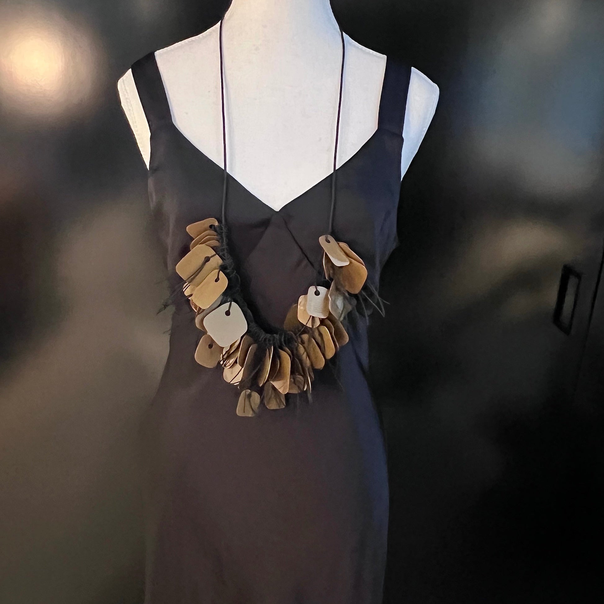 A mannequin wears a necklace made from bronze coloured recycled plastic