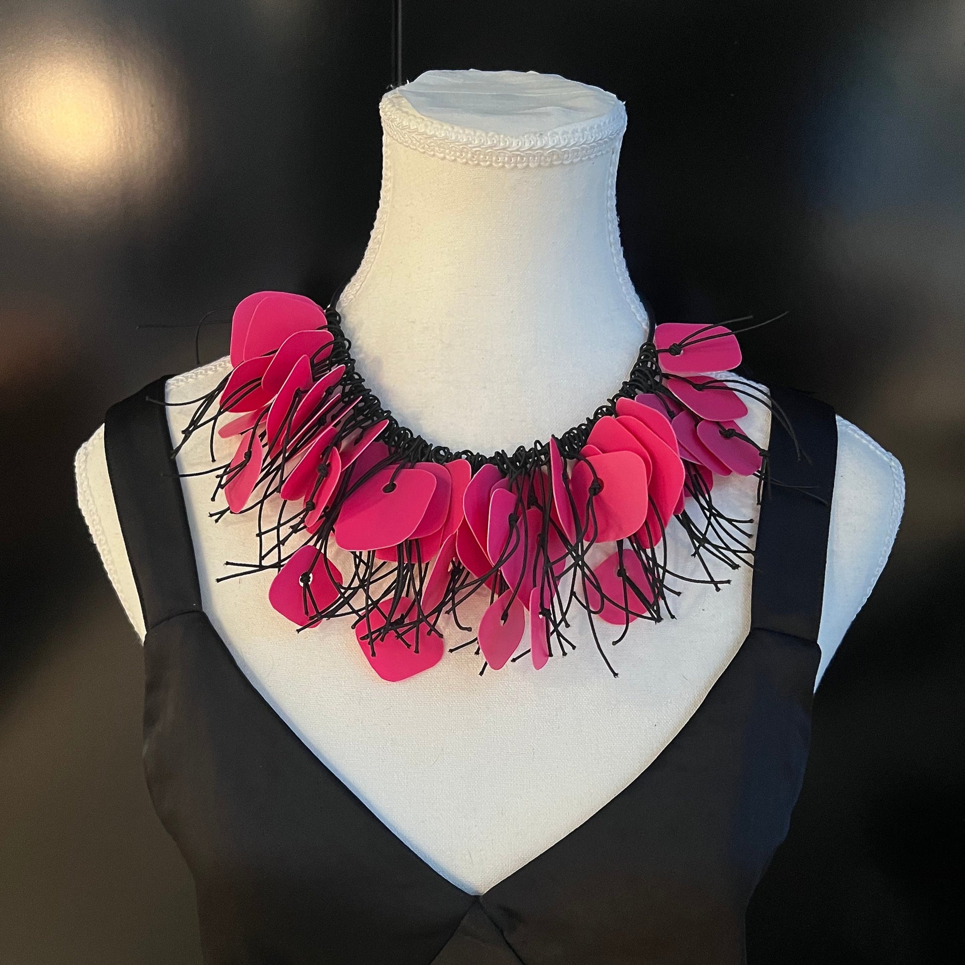 A mannequin wears a necklace made from pink coloured recycled plastic as a choker