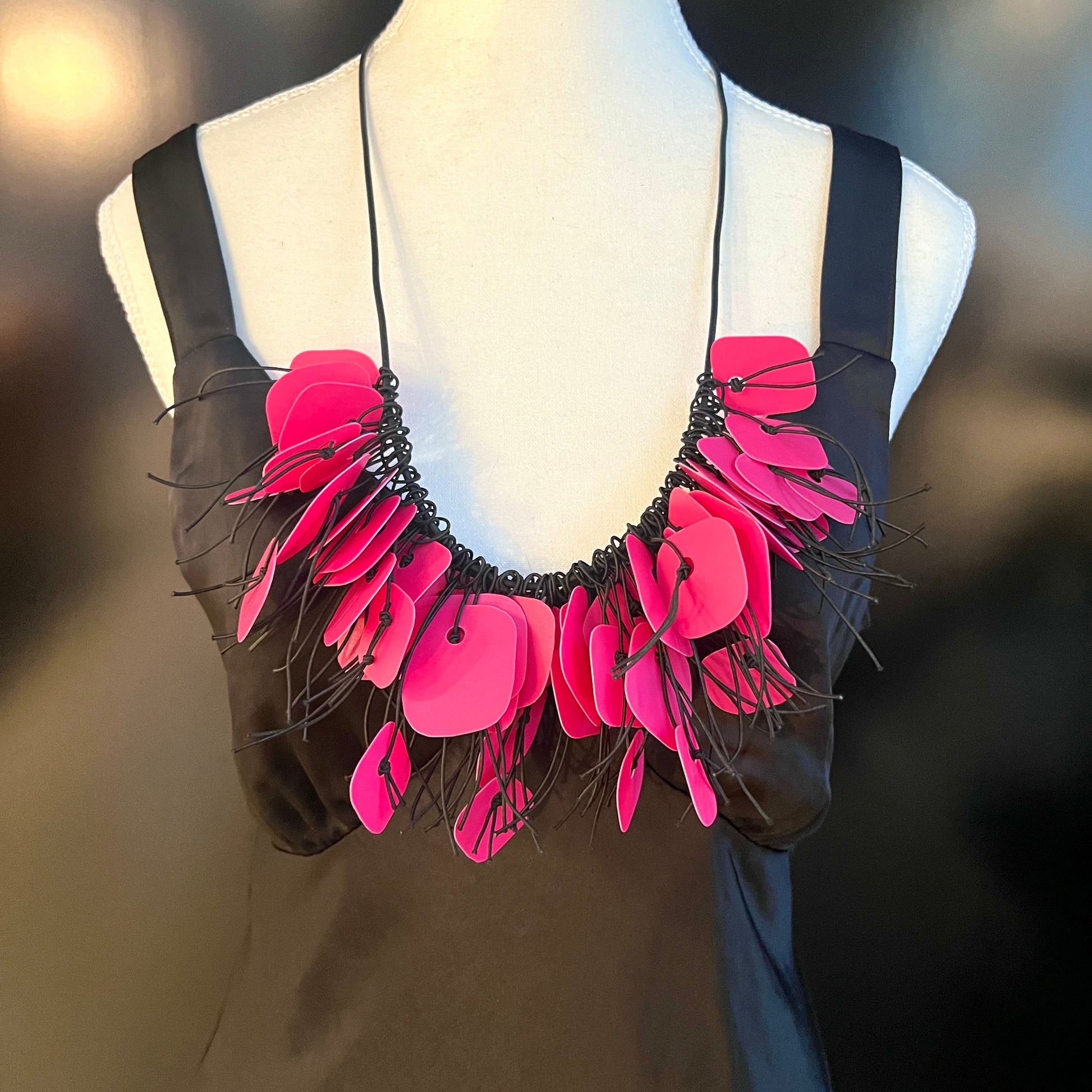 A mannequin wears a necklace made from pink coloured recycled plastic