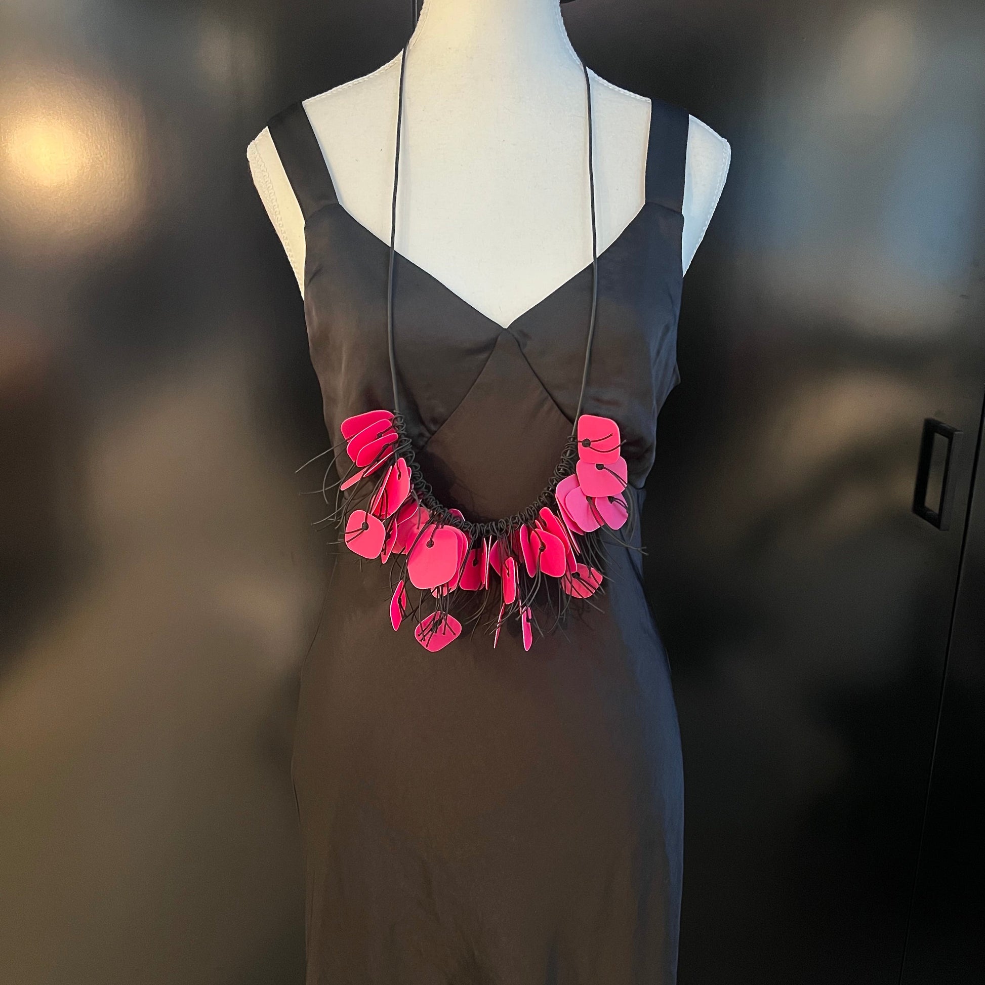 A mannequin wears a necklace made from pink coloured recycled plastic