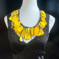 Yellow floral necklace on a mannequin against a dark background
