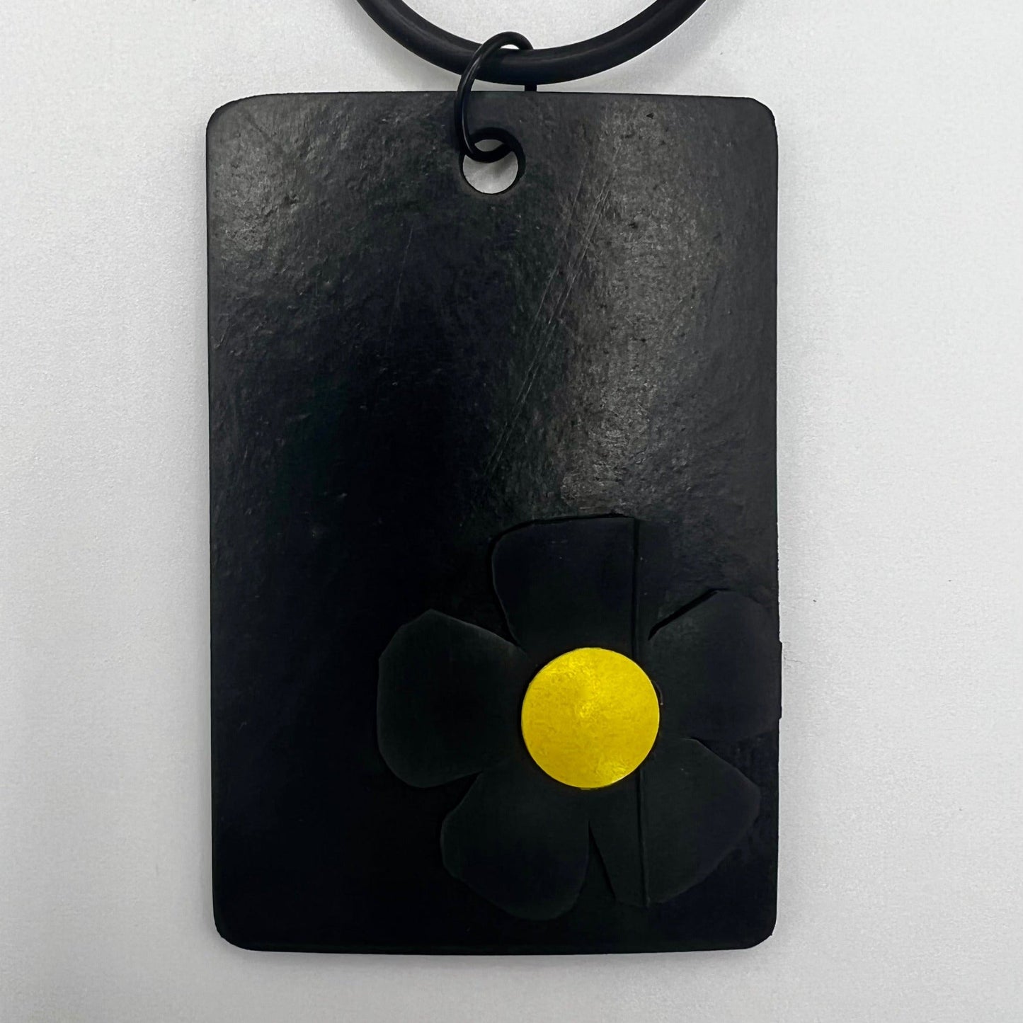 A black rubber pendant with a black and yellow daisy