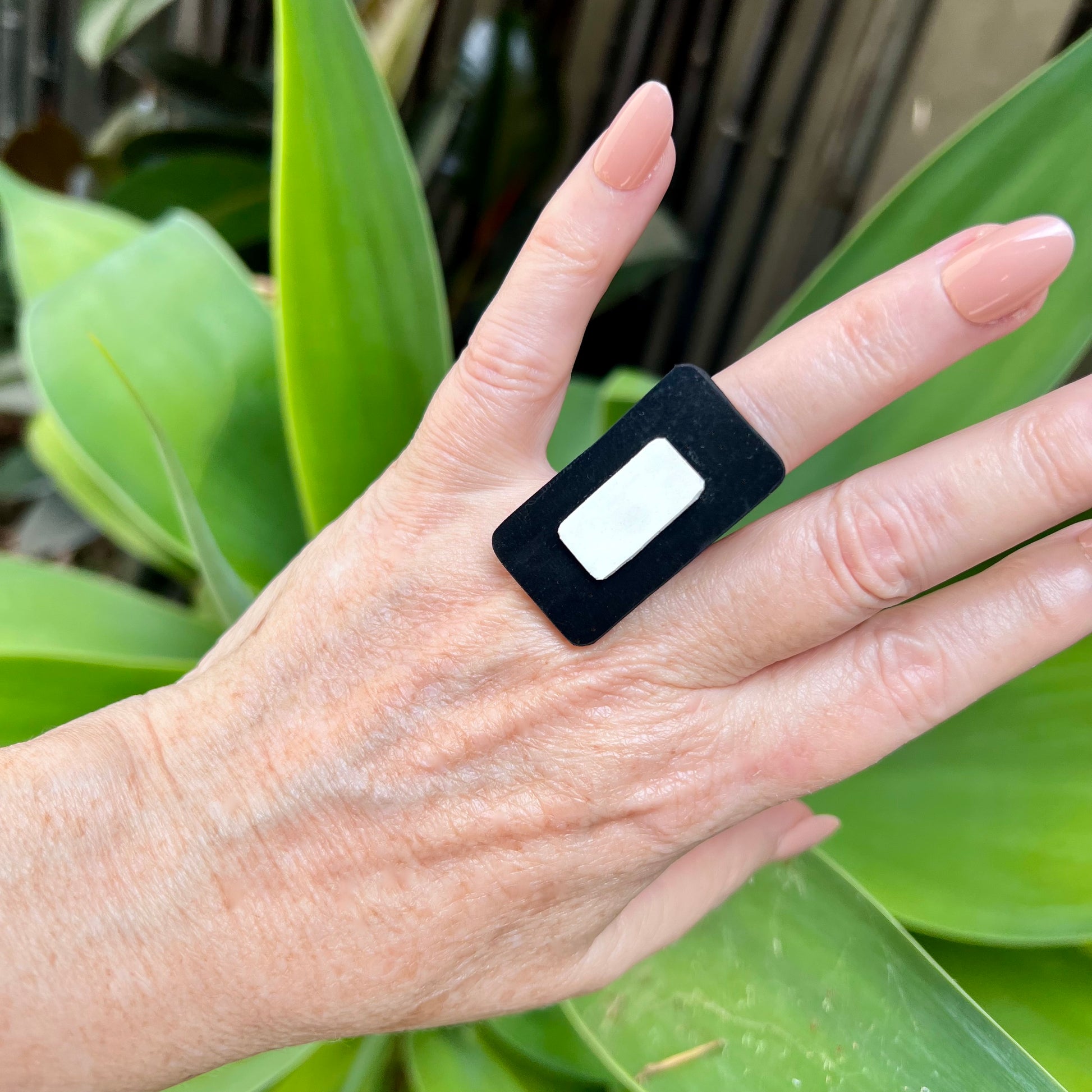 A woman's hand wears a rectangular black and white ring