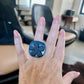 A woman wears a ring topped with a black rubber daisy