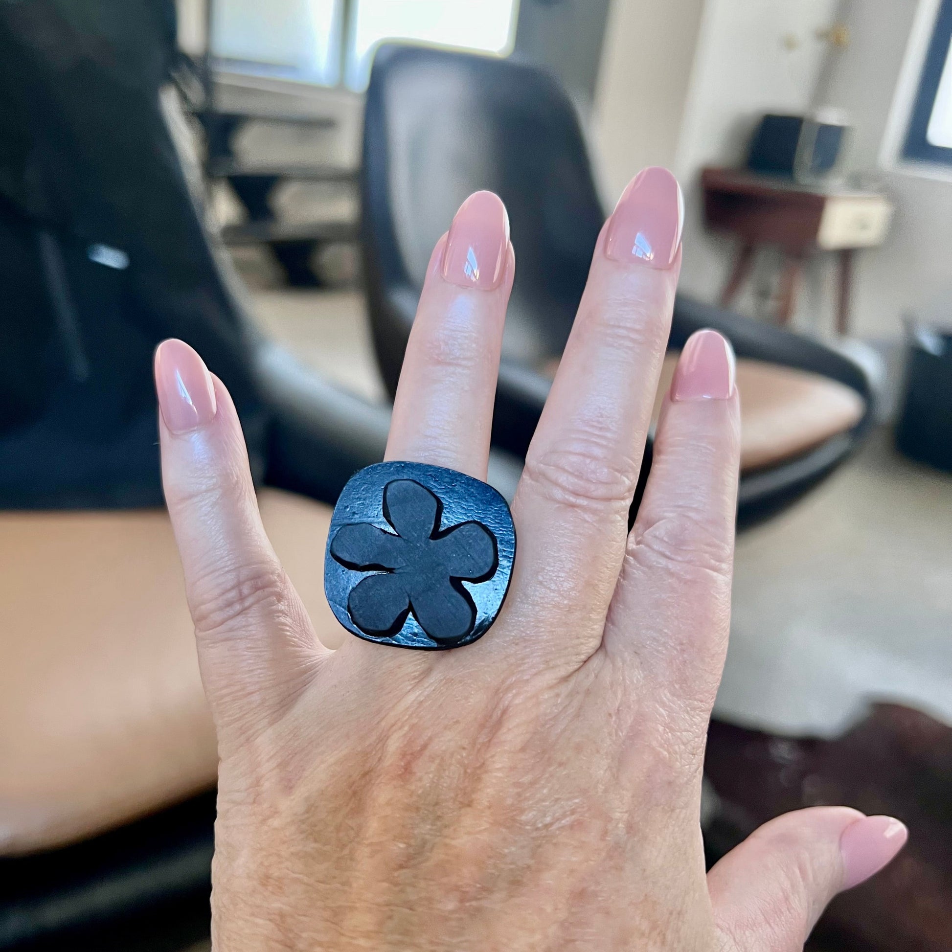 A woman wears a ring topped with a black rubber daisy