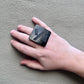 A woman's hand wearing a black square ring