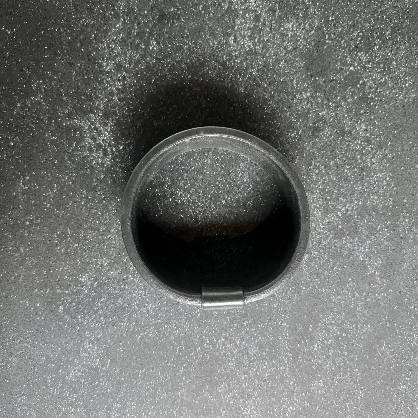 Top shot of A rubber cuff bangle with a strip of black rubber