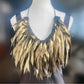 Gold painted recycled rubber necklace on a mannequin against a blurred background
