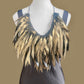 A gold painted rubber necklace worn in a longer length on a mannequin