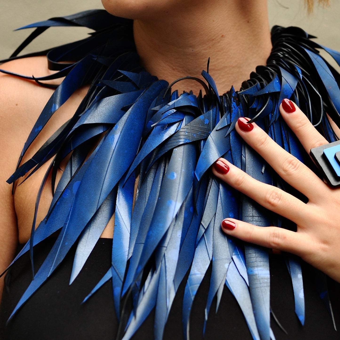 A woman wears a large blue rubber necklace