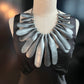 A mannequin wearing a large silver rubber necklace
