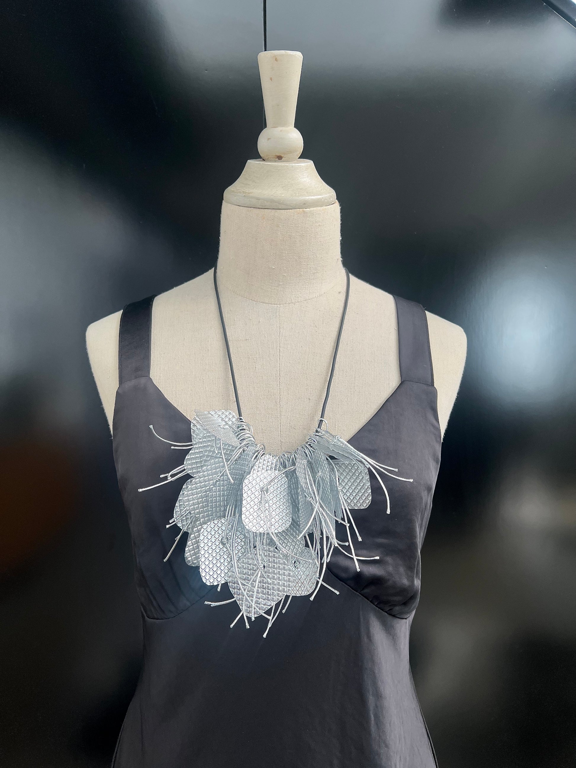 A mannequin wears a silver bouncy necklace