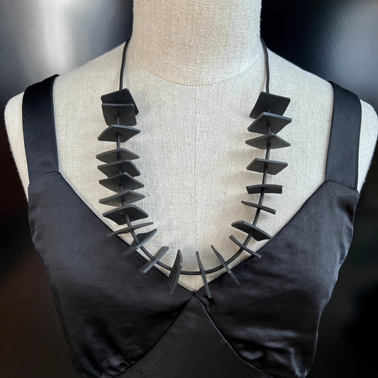 A mannequin wears a necklace of small rubber squares