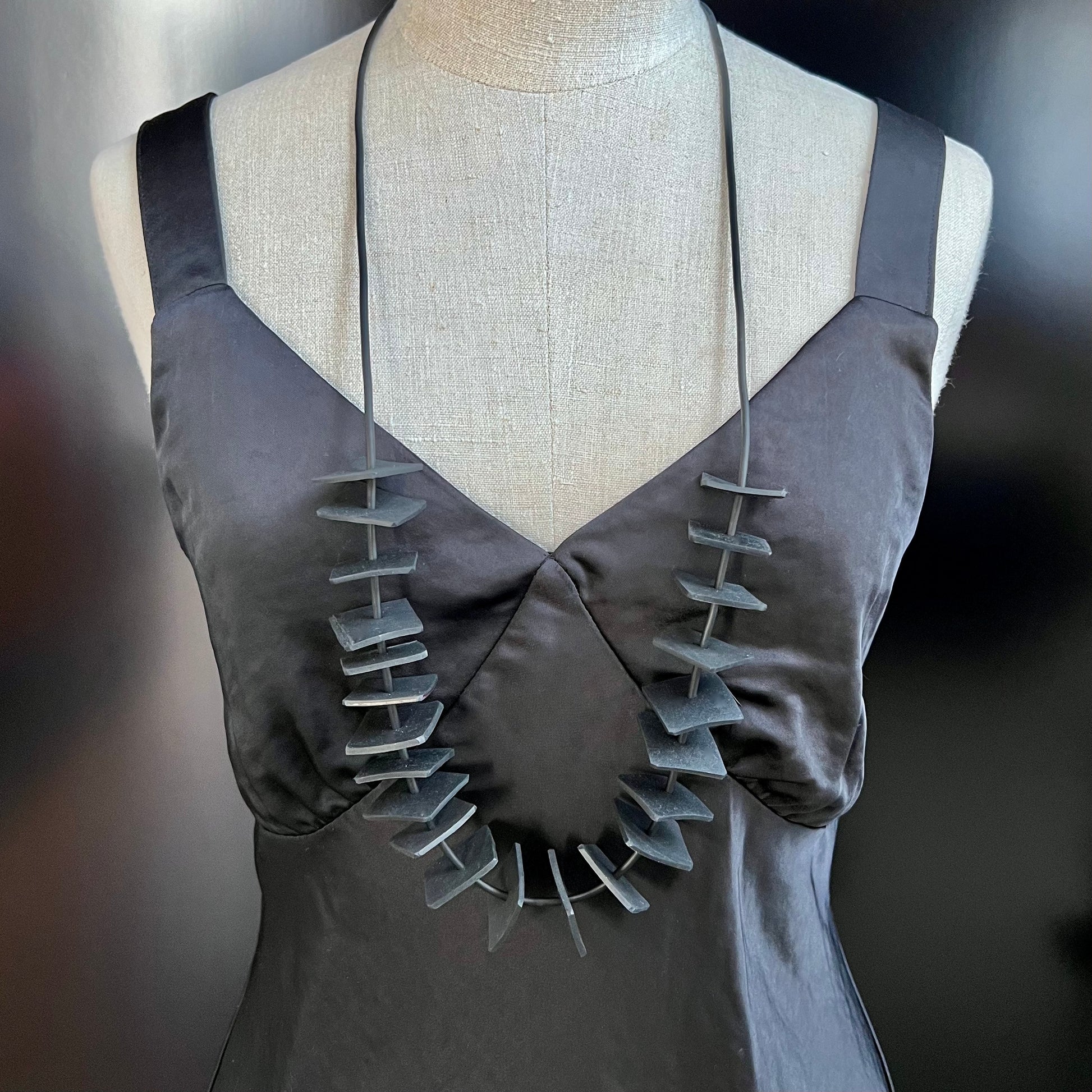 A mannequin wears a long necklace of small rubber squares