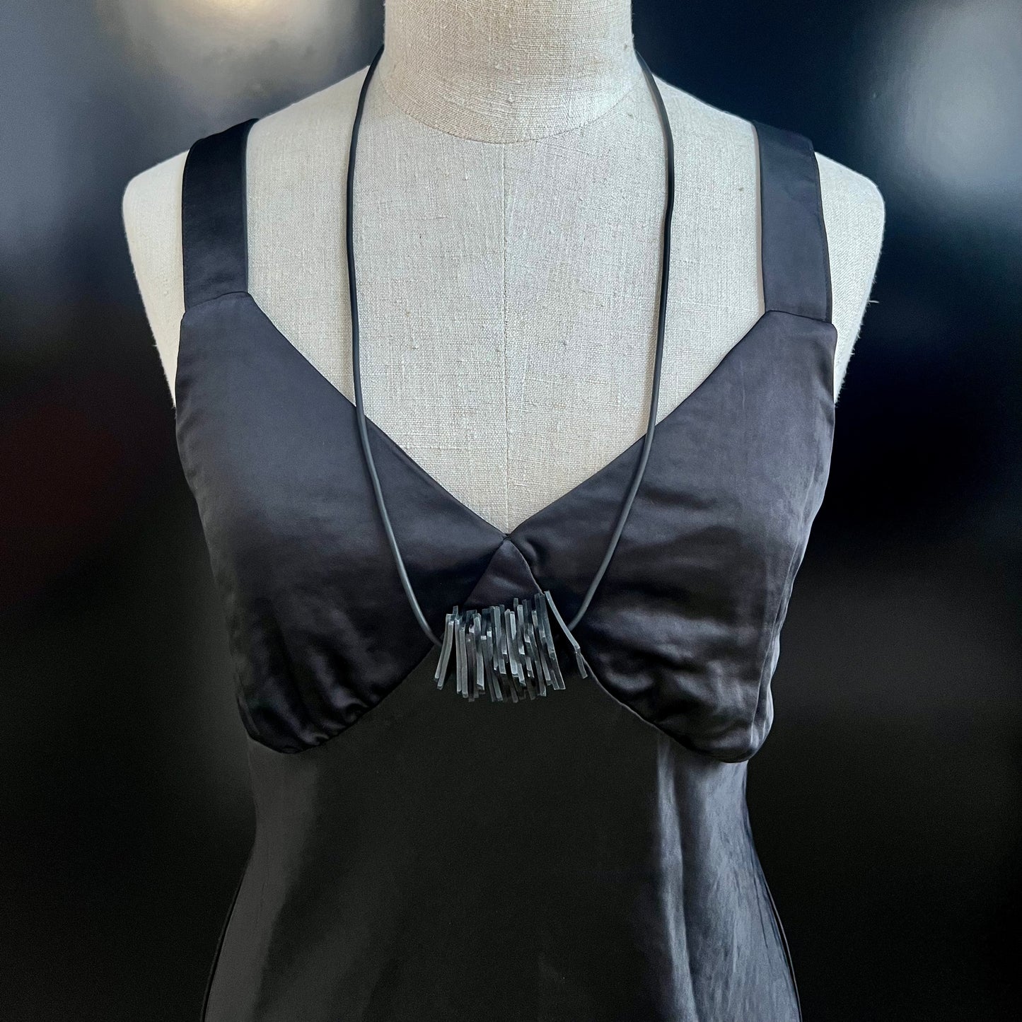 A mannequin wears a necklace with small squares bunched together