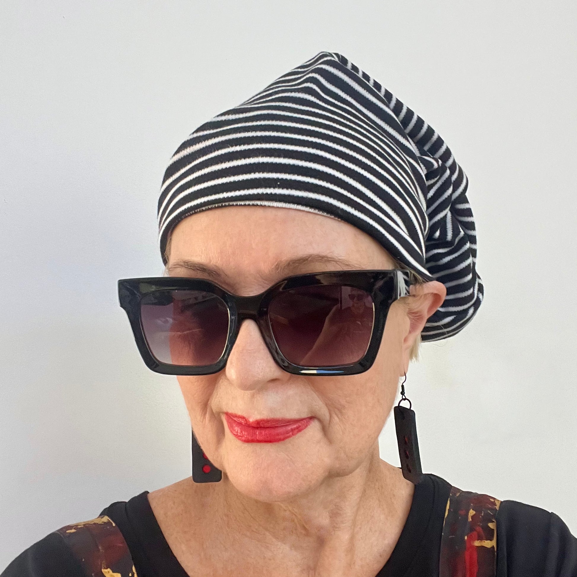 A woman wears a stripe stretchy tube style hat