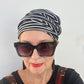 A woman wears a stretch stripe tube style hat, scrunch high on her head