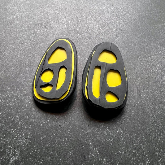 A pair of yellow and black earrings with fossil like segments