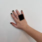 A woman&#39;s hand wearing a big black square ring made from reclaimed industrial rubber