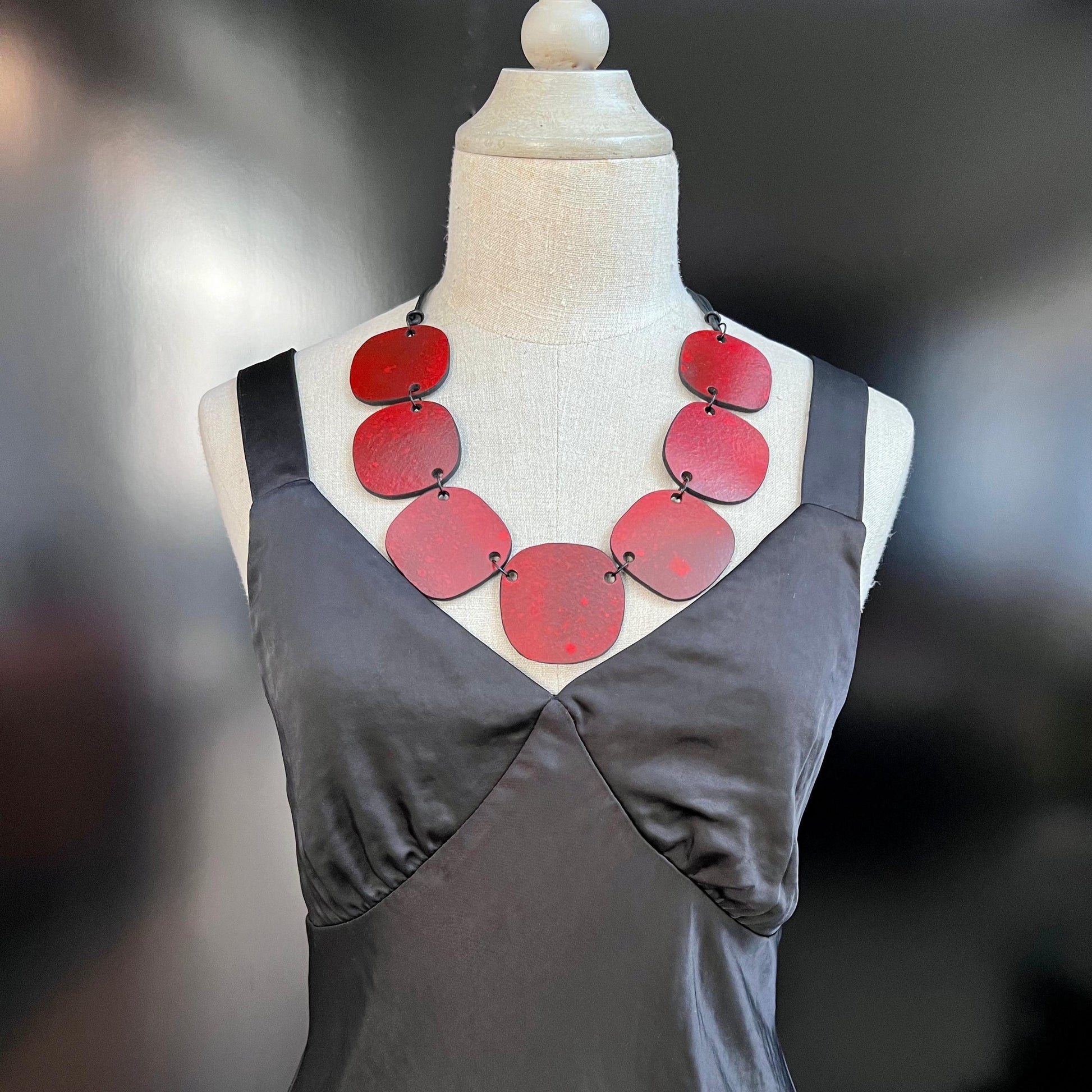 A mannequin wears a red spray painted rubber necklace