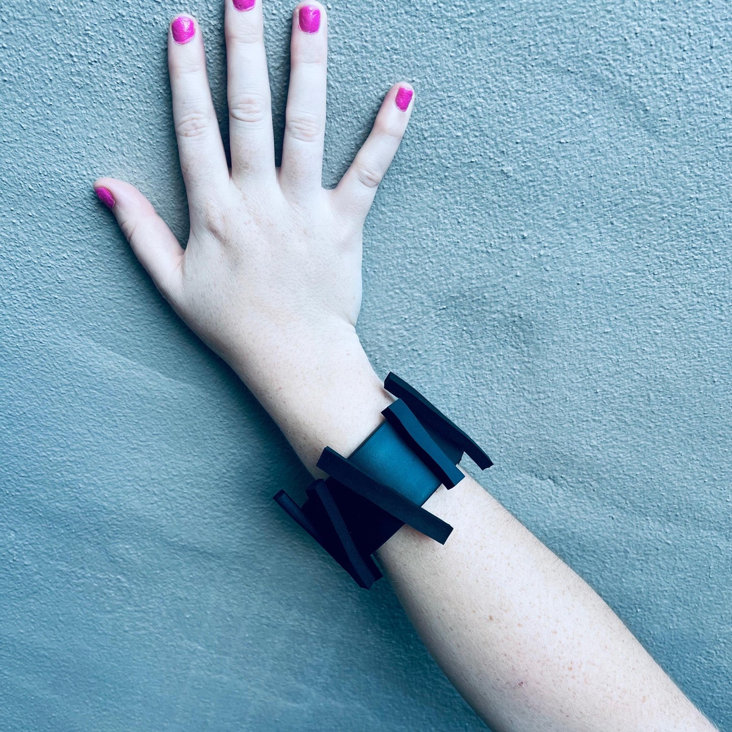 An arm wearing a black rubber bangle