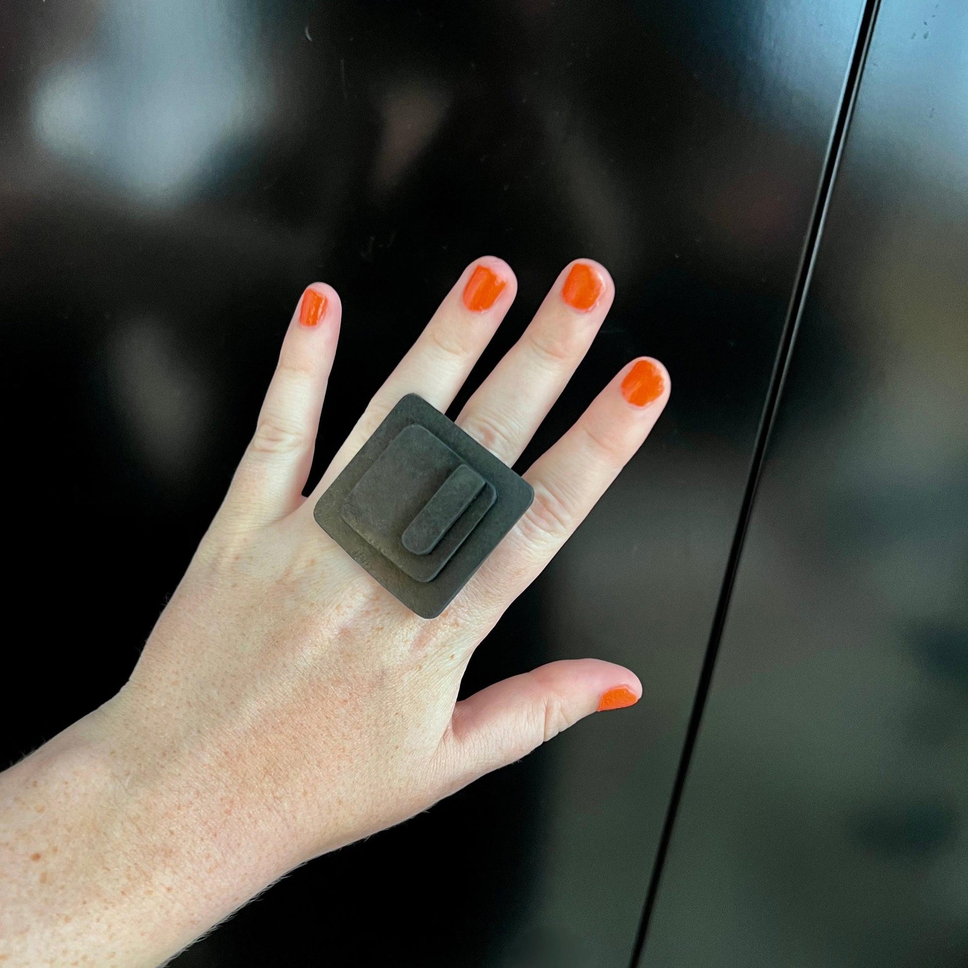 A woman&#39;s hand wears a large black rubber ring