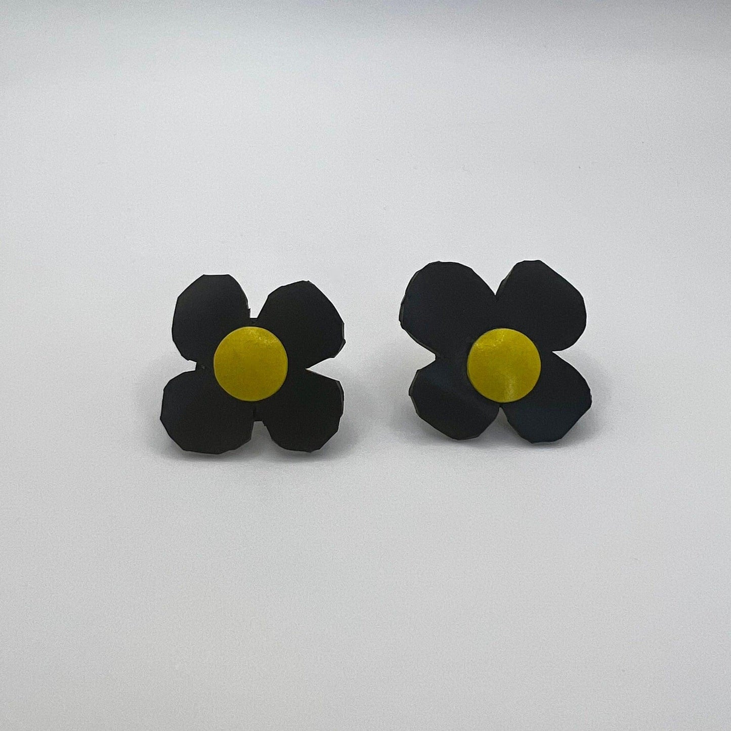 A pair of black and yellow daisy shaped earrings