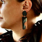 A woman wears a long hand painted earring