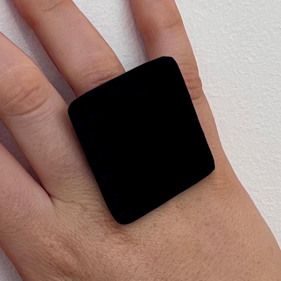 A woman&#39;s finger wearing a big black square ring made from reclaimed industrial rubber