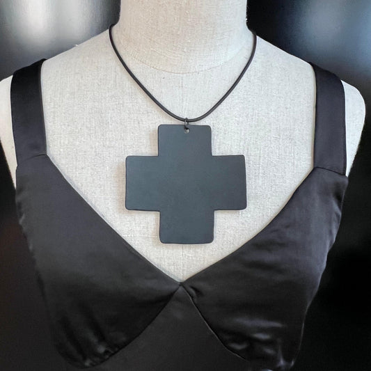 A mannequin wears a large black rubber cross pendant necklace