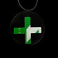 A round black pendant with a green and white cross overlay