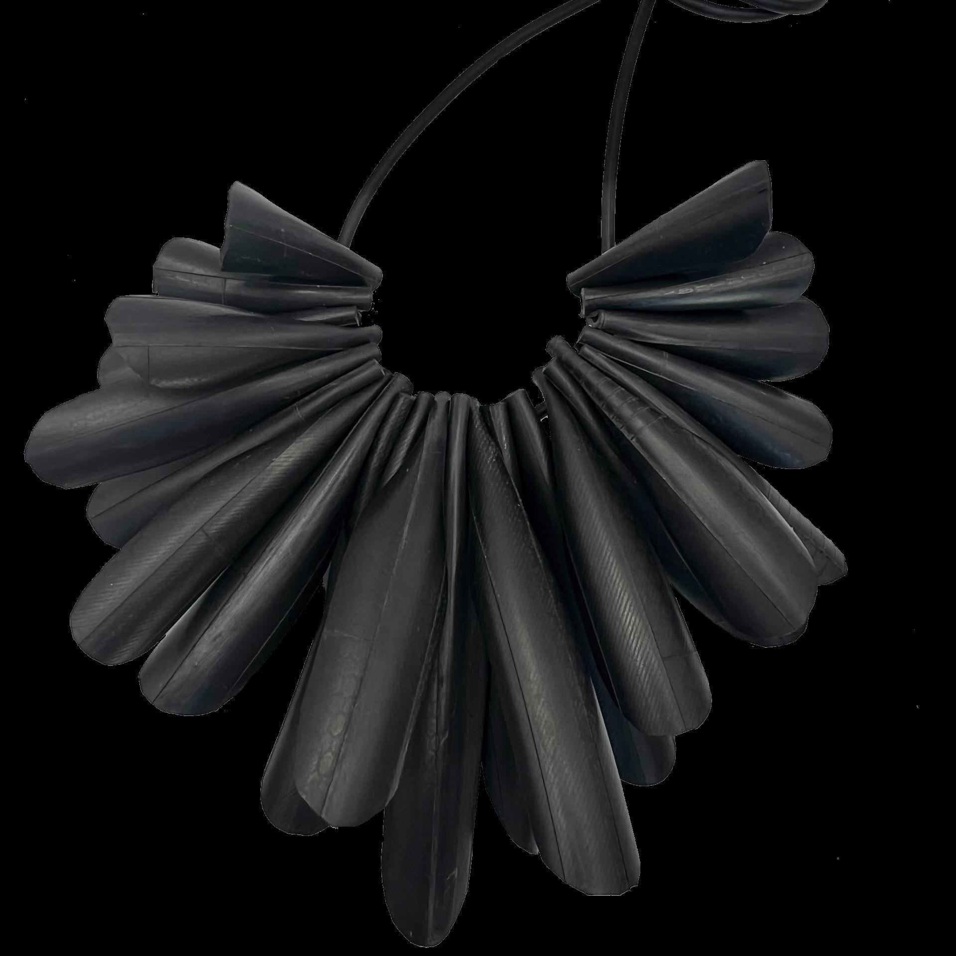 A necklace made up of pieces of bicycle inner tube that resembles a flower with no background