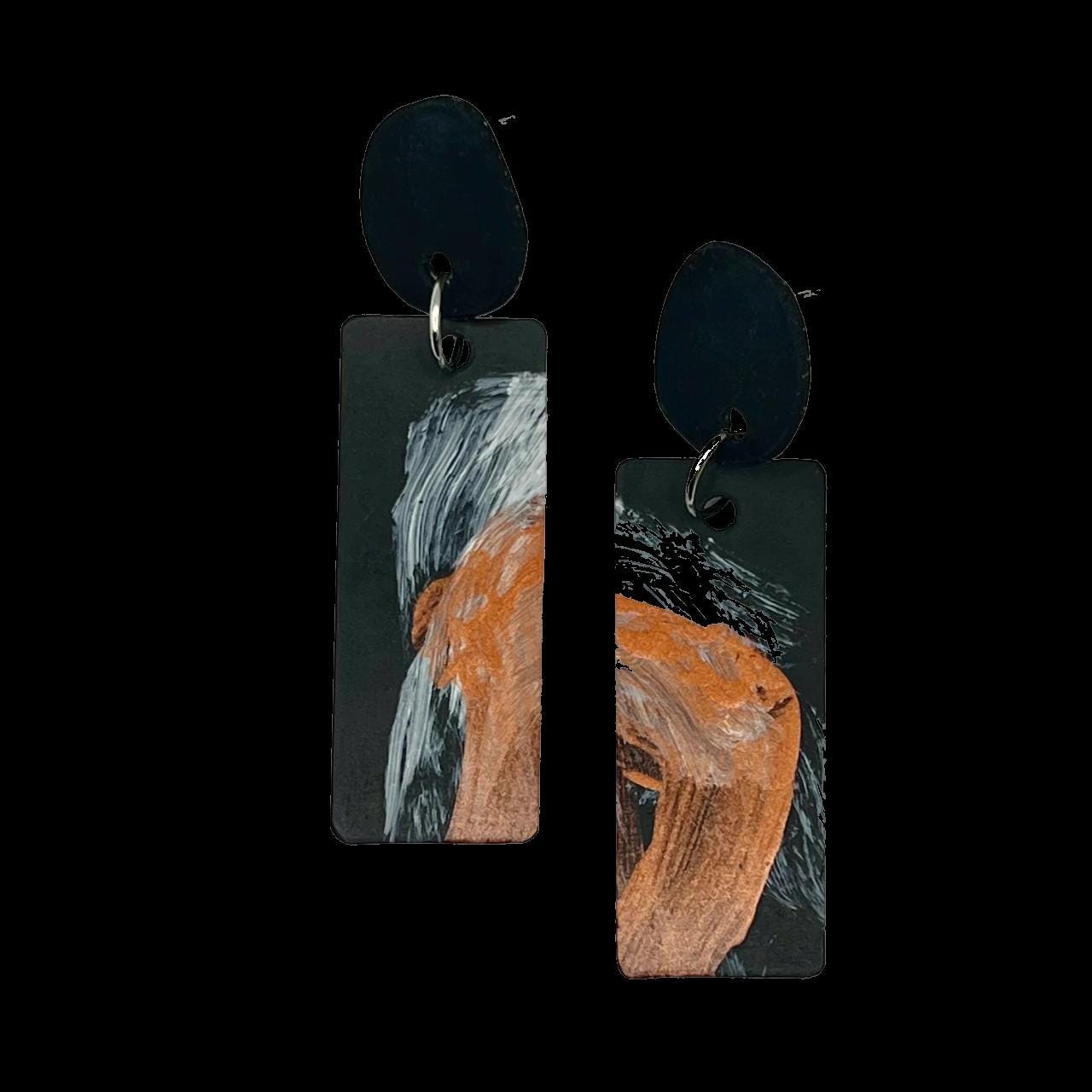 A pair of abstract metallic painted earrings on rubber