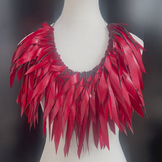 A mannequin displays a large red voluminous necklace