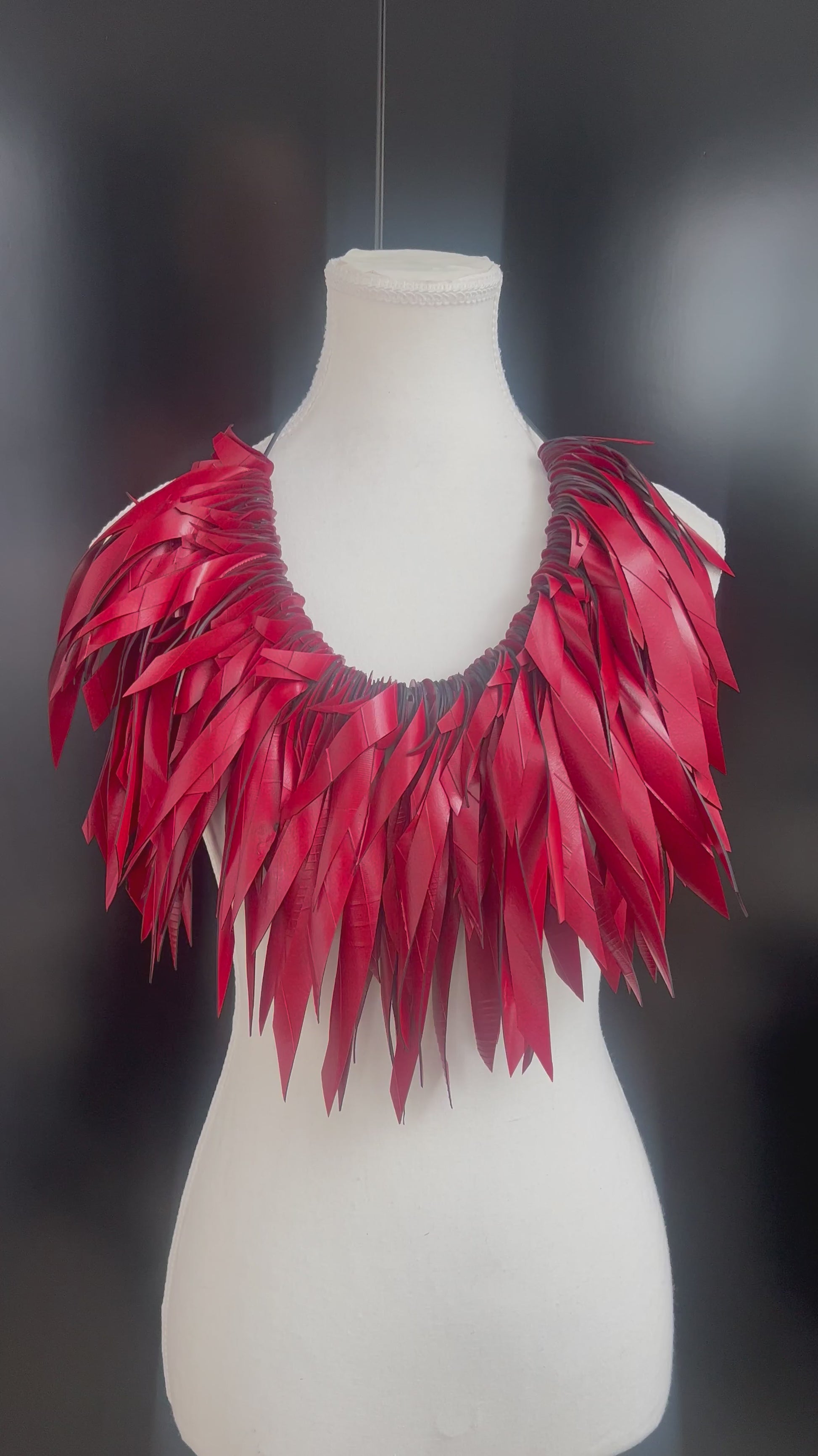 A mannequin displays a large red voluminous necklace