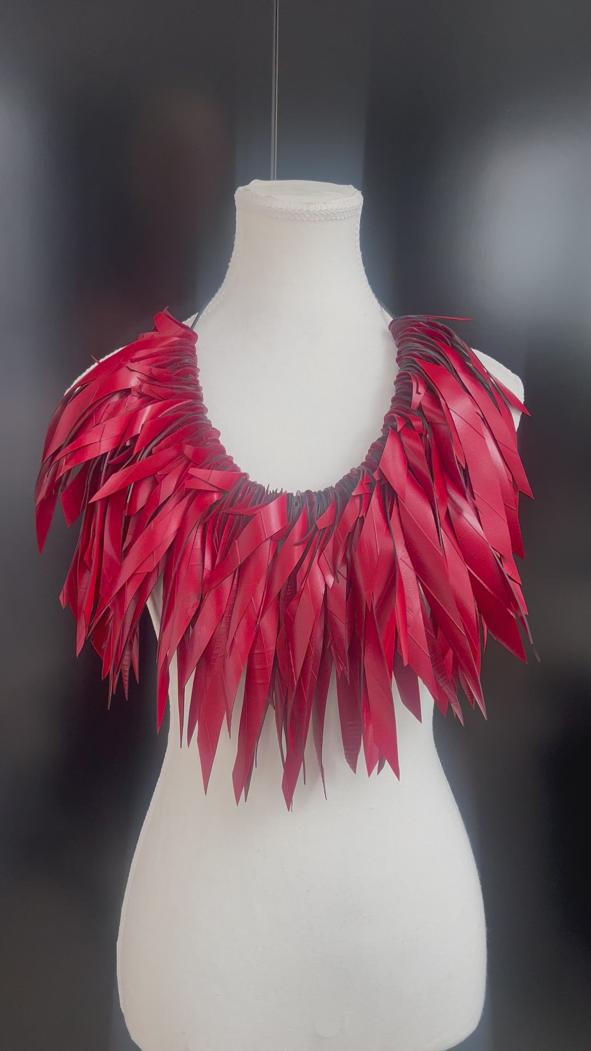 A mannequin displays a large red voluminous necklace