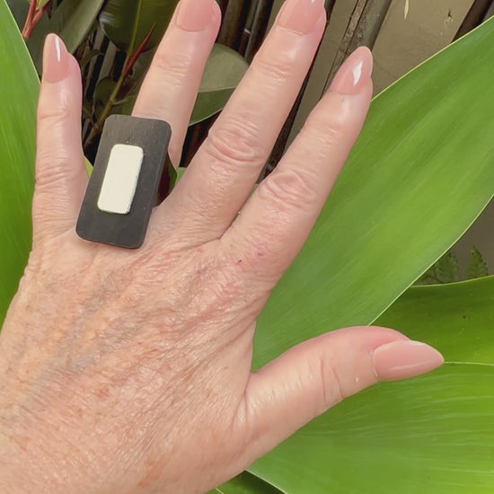 A woman's hand wears a rectangular black and white ring
