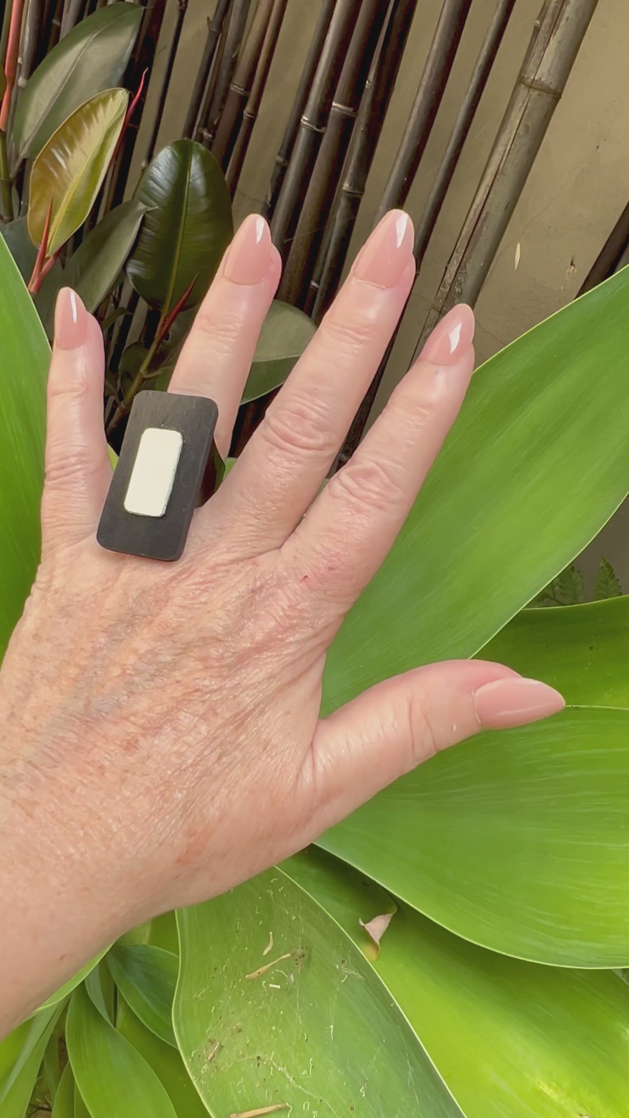 A woman's hand wears a rectangular black and white ring